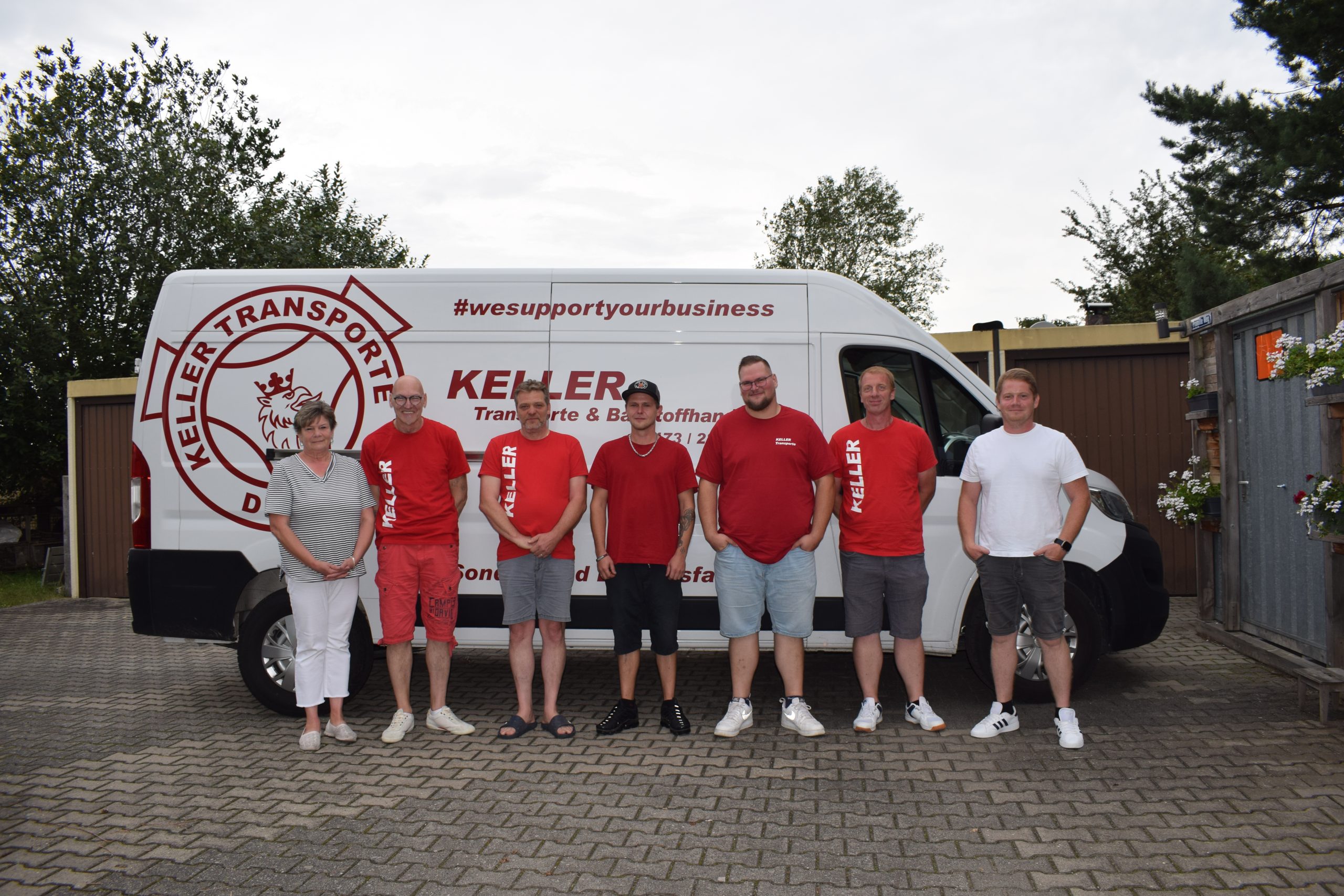 Ein Gruppenfoto von den Mitarbeitern von Keller Transporte & Baustoffhandel vor einem Transporter mit der Aufschrift "KELLER TRANSPORTE"